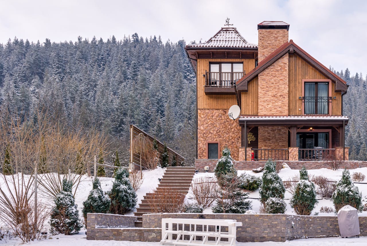 A picturesque chalet in winter with snow-capped terrain and a serene forest backdrop.